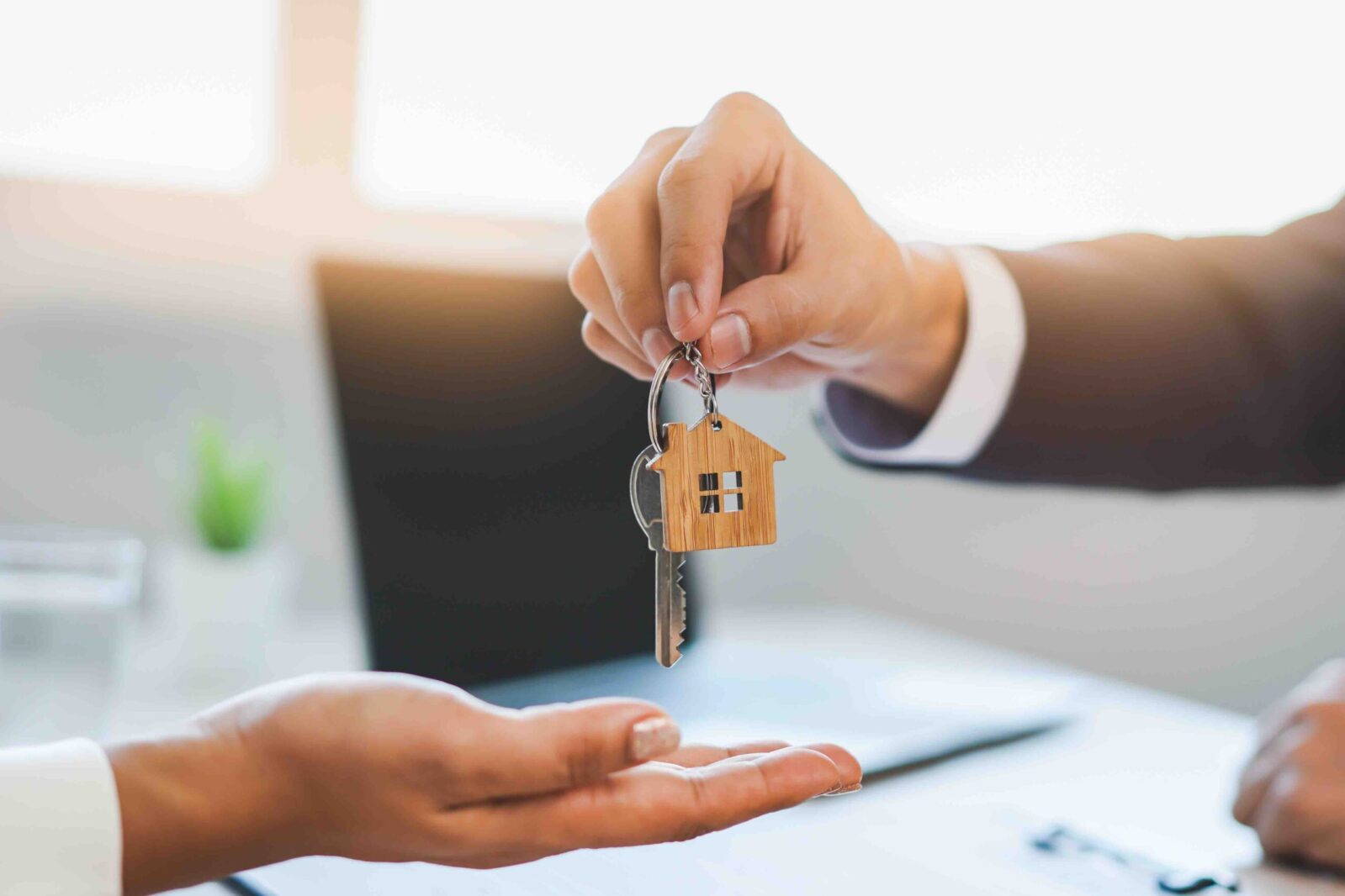 close up view hand of property realtor / landlord giving key house to buyer / tenant.